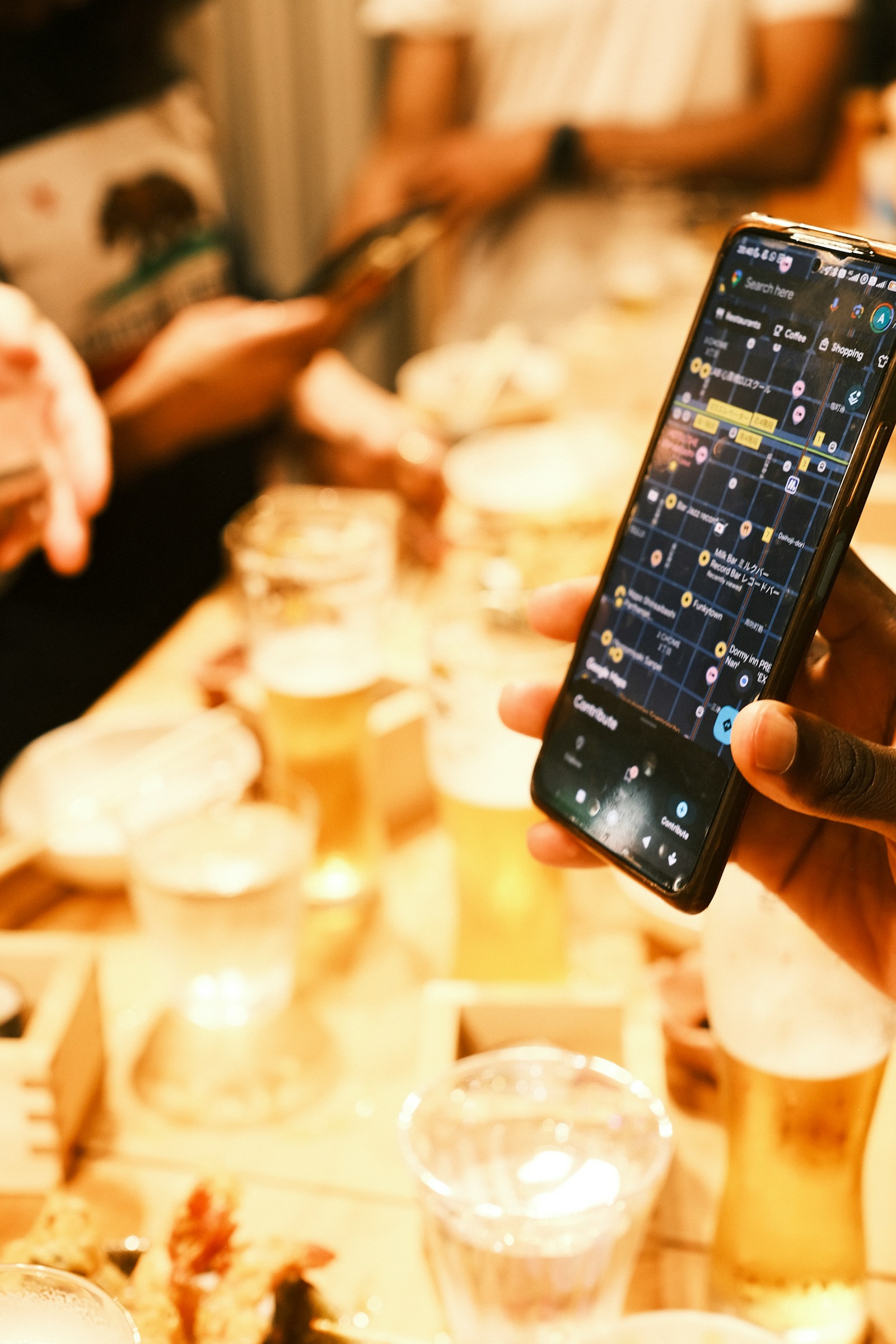 A hand holding a phone showing a map app with nearby local business pins